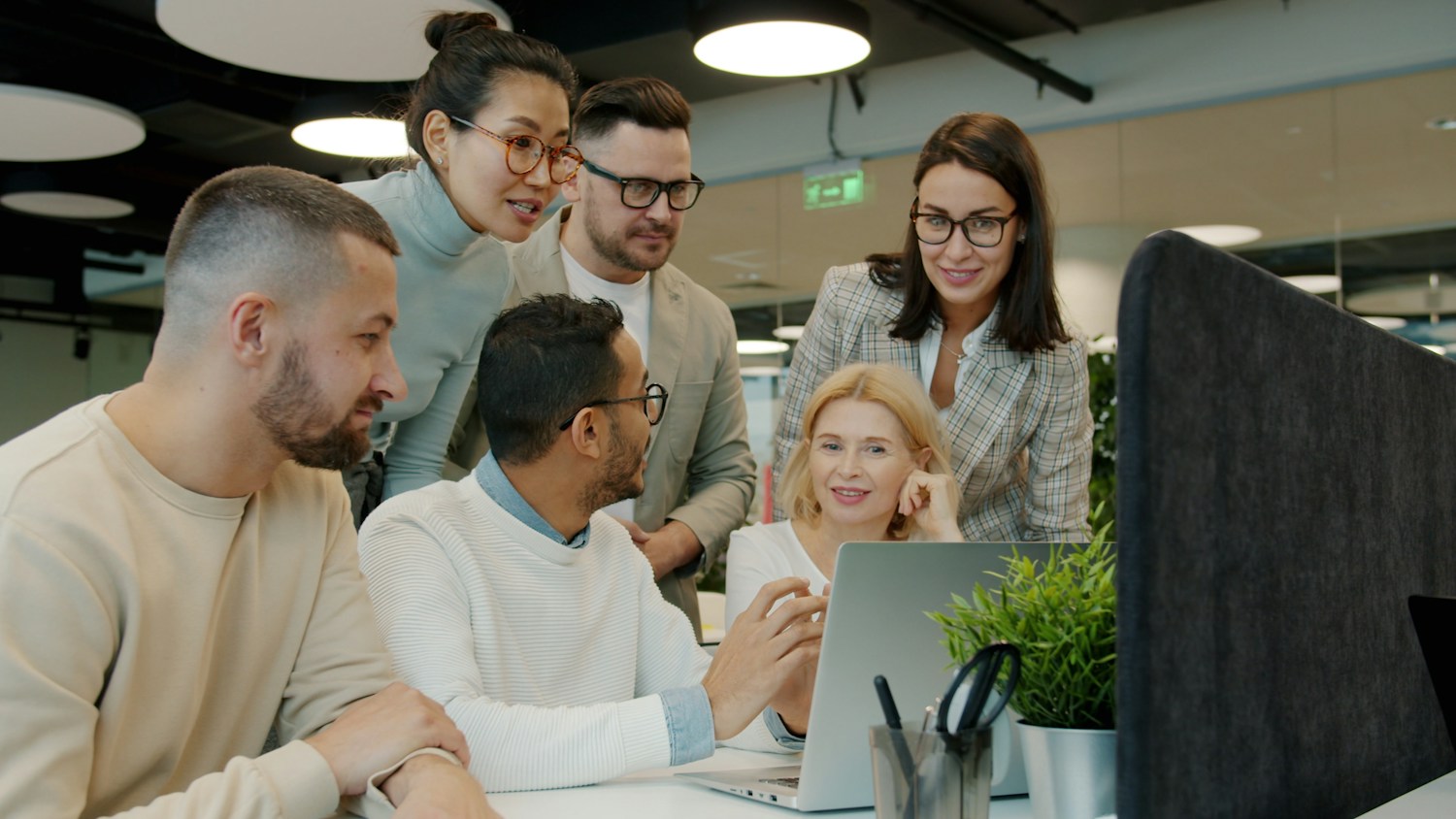 A group of colleagues discussing ideas together around a laptop.